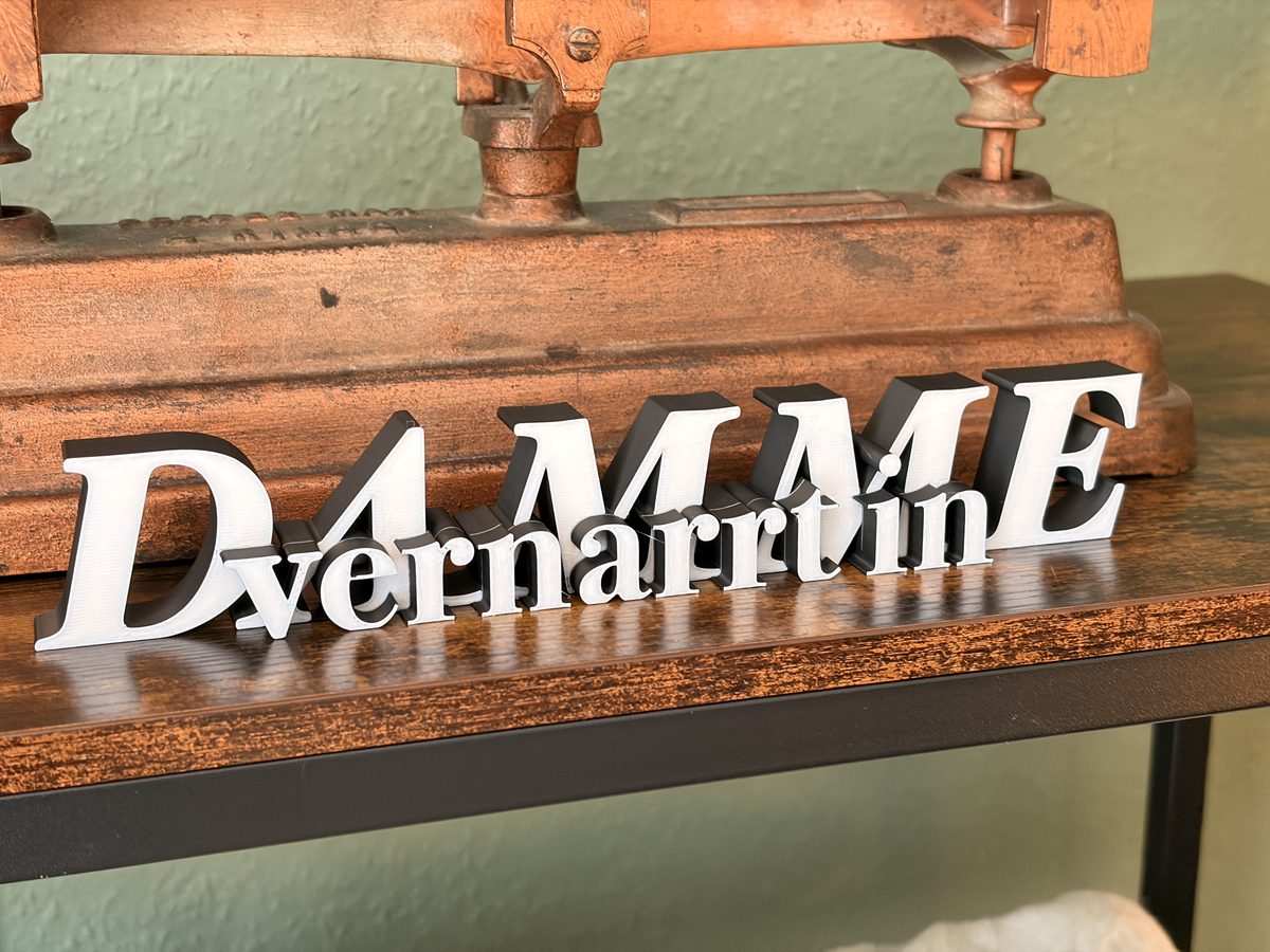 Der „Vernarrt in Damme“-Aufsteller in Schwarz-Weiß vor einer alten Buchpresse